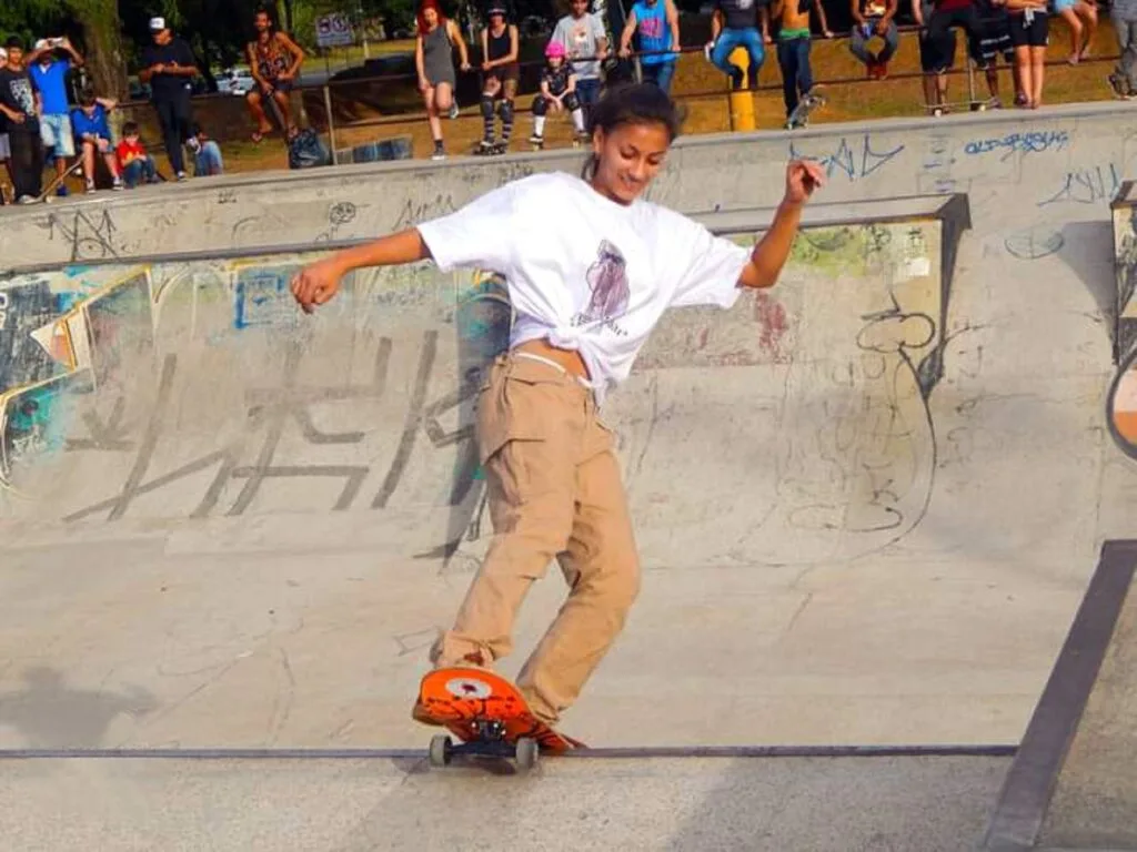 Jovem de camiseta branca faz manobra no skate