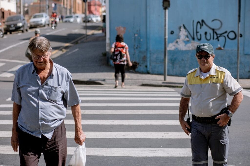 Agente de trânsito observa pedestre atravessando a faixa de pedestre