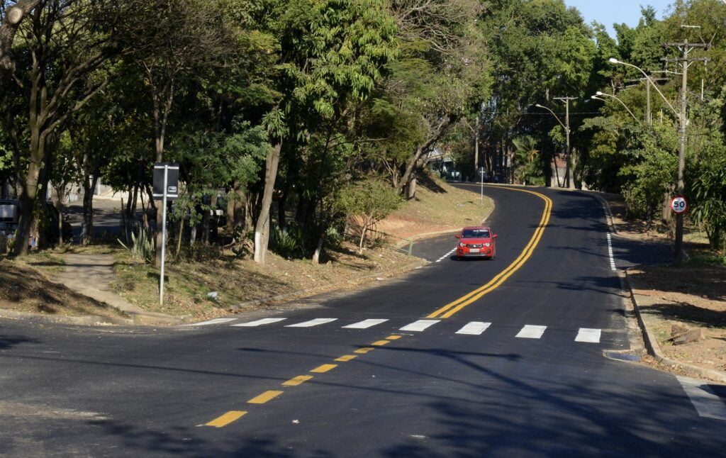Imagem da avenida Cristóvão Colombo recapeada, com árvores ao fundo e um carro vermelho passando