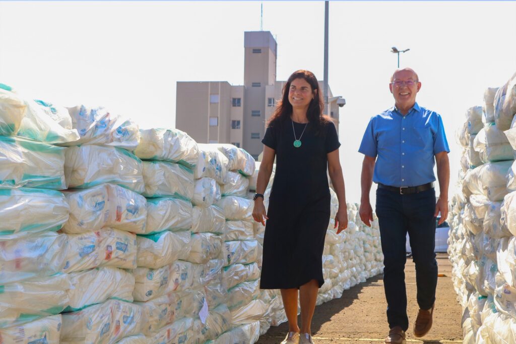 A presidente do Fuusp, Andreia Almeida, de vestido preto, caminha ao lado de homem com camisa azul