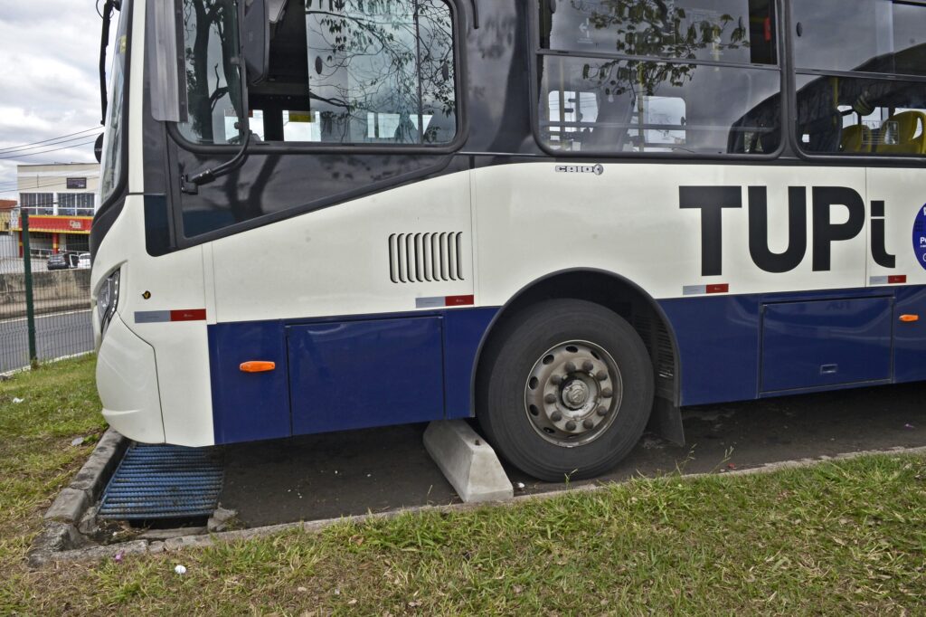 Imagem de ônibus estacionado, mostrando a lateral dele, com destaque para o bate-rodas da vaga