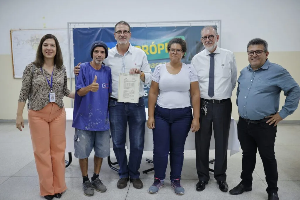 Casal que recebeu a documentação junto do prefeito e secretários municipais, todos em pé