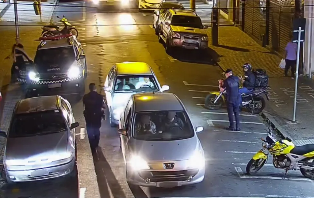 Imagem mostra o momento em que três guardas municipais fazem a revista no suspeito