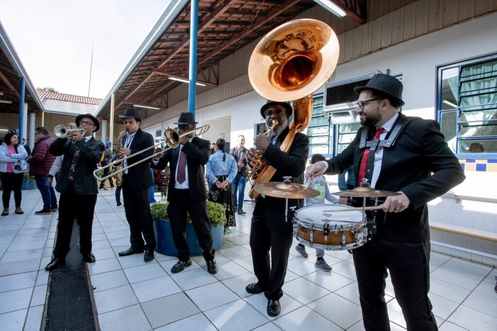 Músicos com instrumentos musicais tocando em escola.