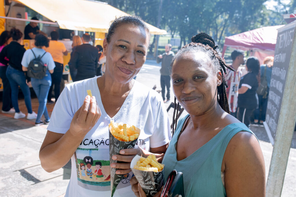 Duas mulheres comem um salgado durante evento realizado na rampa do Centro Cívico