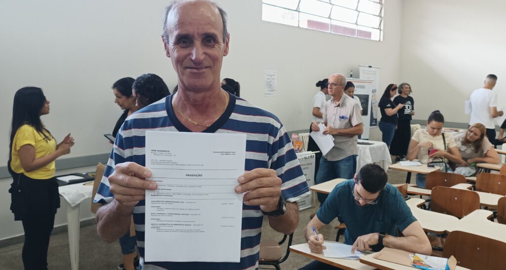 Imagem do motorista José Munerato, sorrindo, segurando seu currículo 