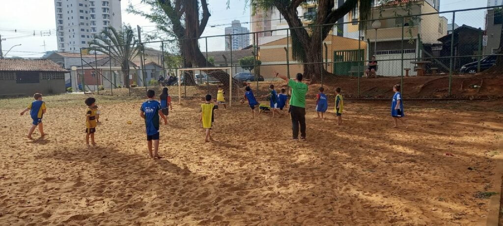 crianças  jogam futebol em campo de areia