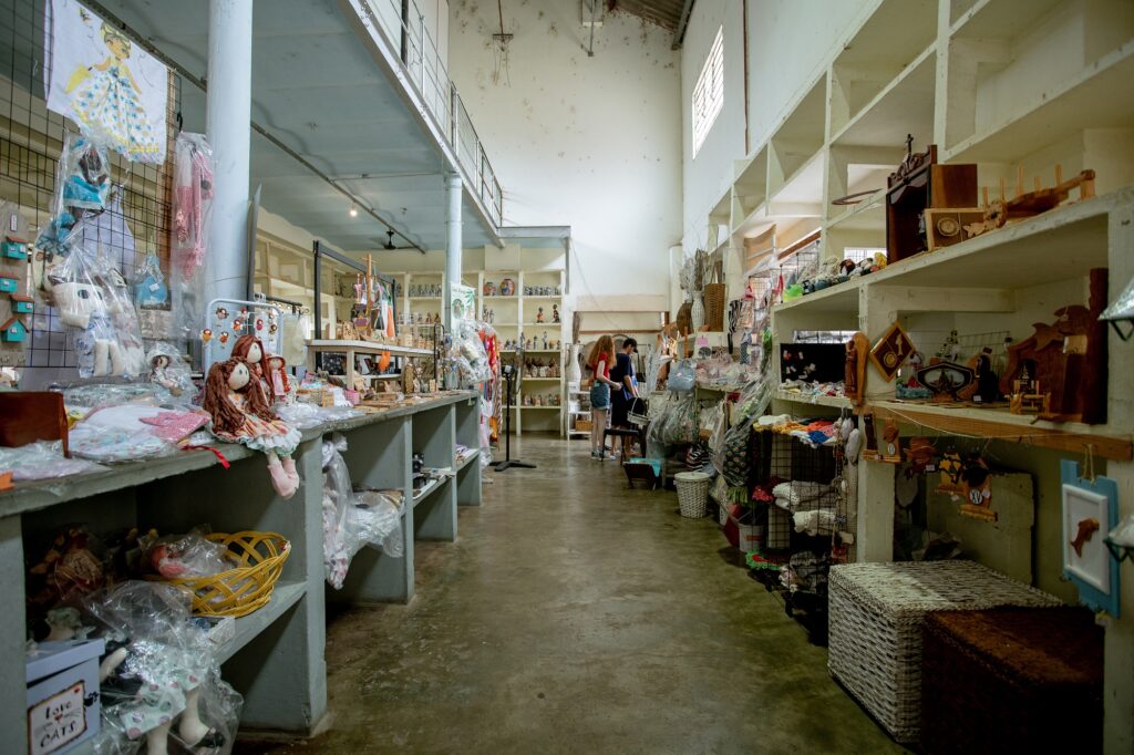 Imagem interna da Casa do Artesão, com diversos produtos expostos, como bonecas, quadros, caixas, porta-retratos, entre outros itens feitos por artesãos manualmente