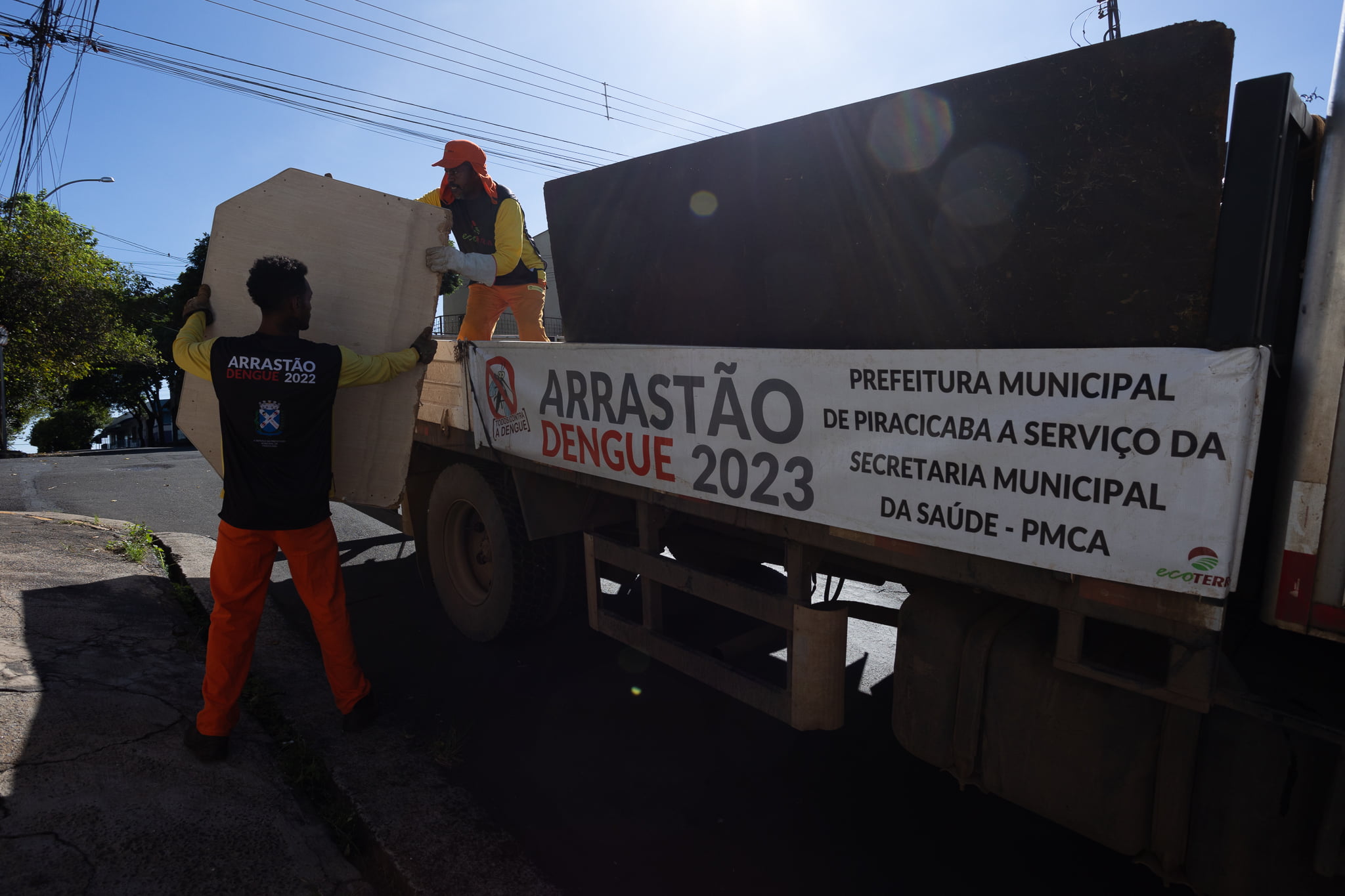 Em um caminhão, com grande carreta, dois servidores fazem o recolhimento de inservíveis na rua como mesas e cadeira quebradas, sofás velhos. Todo o material foi depositado no caminhão e levado para o descarte adequado