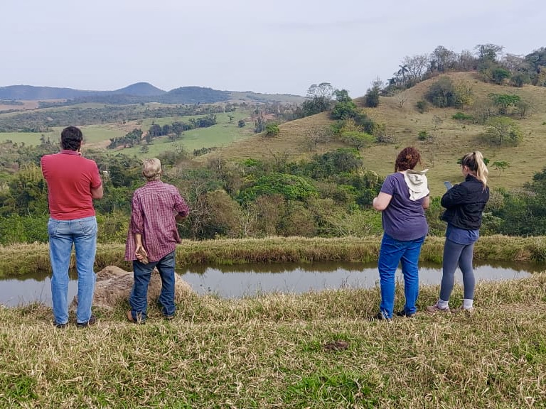 Equipe técnica durante vistoria do programa PSA em propriedade rural, observando um rio na propriedade