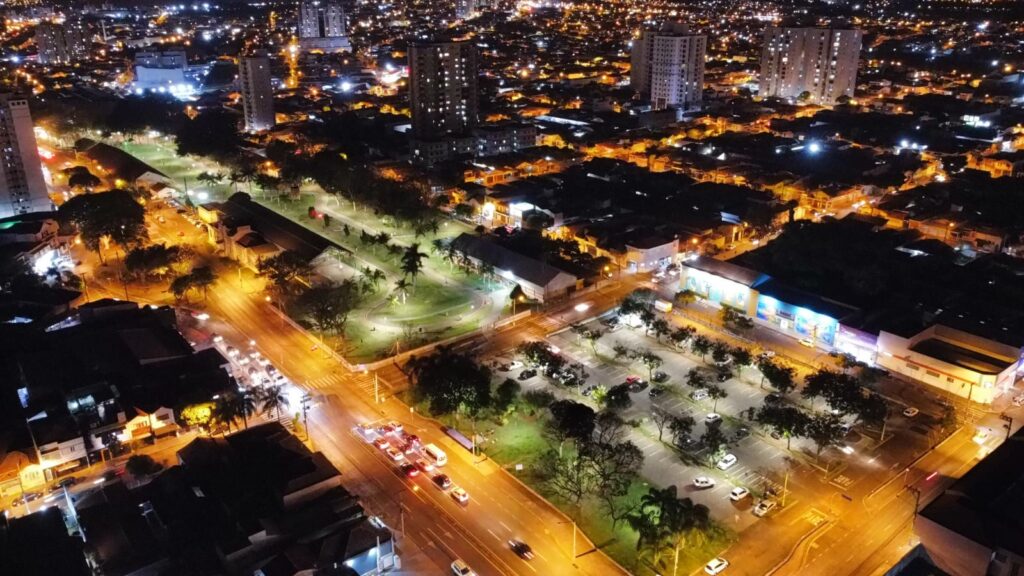 Imagem aérea do bairro Paulista a noite, mostra casas, prédios, carros nas ruas e luzes. Em destaque, a Estação da Paulista iluminada com as novas luminárias