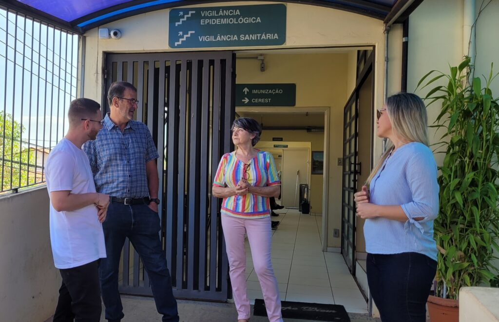 Em frente a porta de entrada, o prefeito Luciano conversa com a Karina e Clarice sobre reformar necessárias no prédio da Cevisa. Ao lado, o vereador Gustavo Pompeo participa da conversa