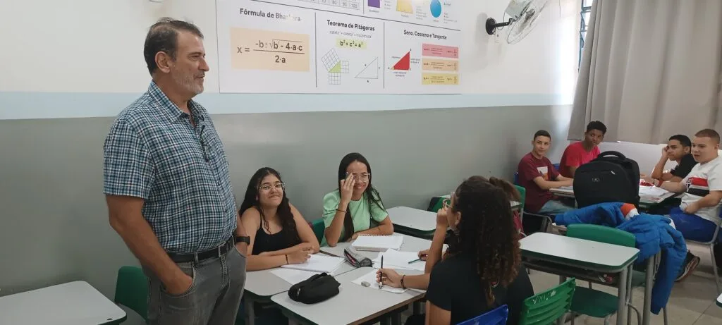 Homem visita sala de aula enquanto alunos o observam .