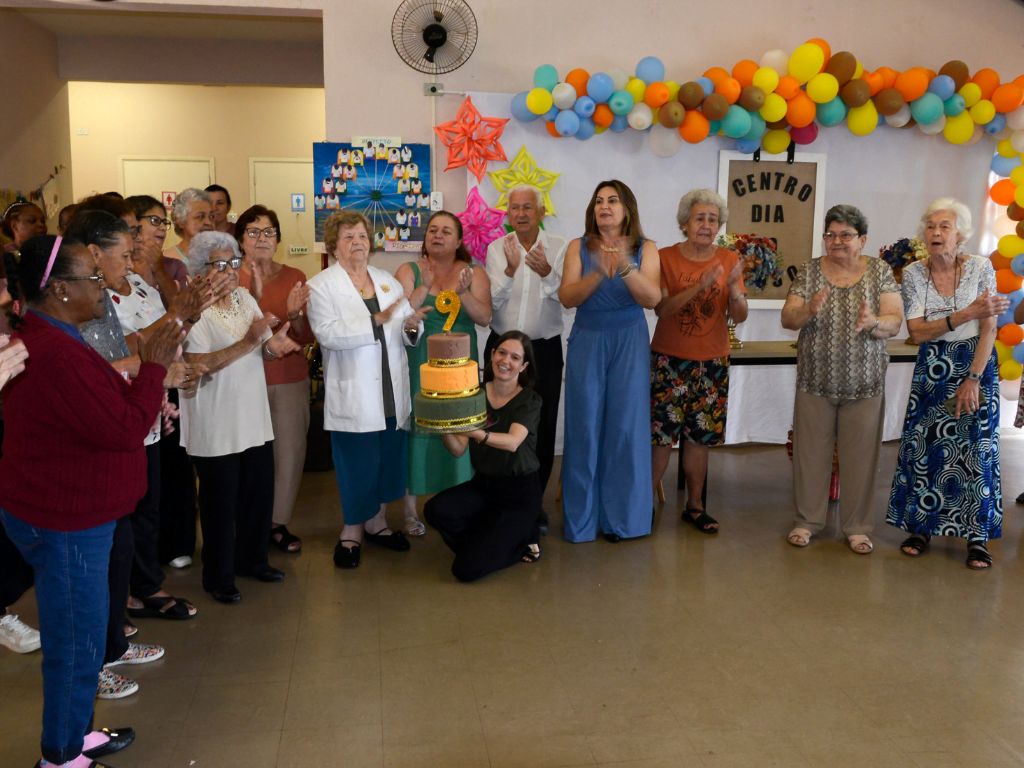 Na foto, imagem de usuários e coordenadores cantando parabéns para o Centro Dia do Idoso