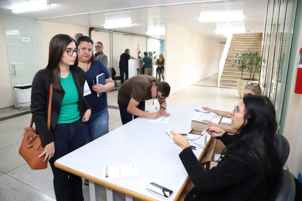 Duas mulheres conversam com atendente de blusa preta