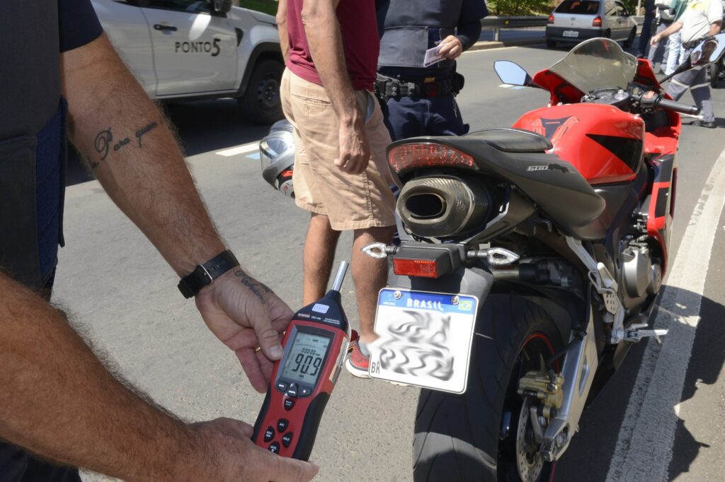 homem segura decibelímetro para medir volume do escapamento de moto