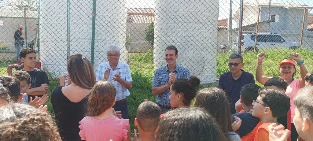 Pessoas celebram a notícia da construção da cobertura e iluminação da quadra da escola.