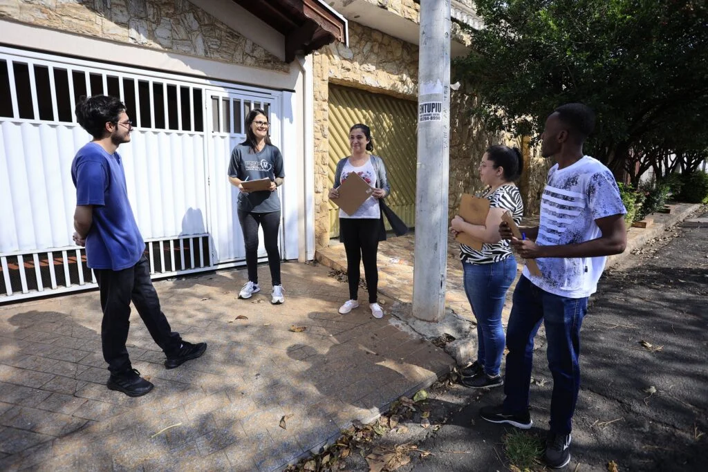 Em frente a uma casa amarela de portão branco parte dos agentes de saúde estão em treinamento na região do PSF Astúrias