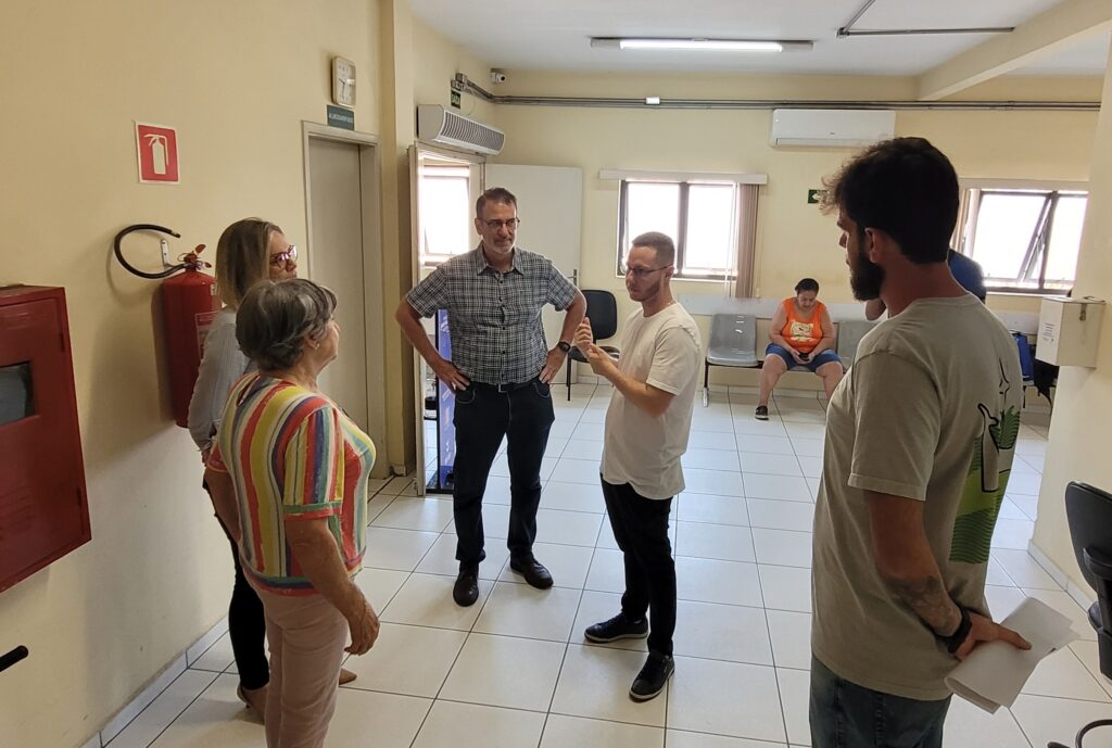 em área de atendimento coletivo, dentro do prédio da Cevisa, Clarice e Karina solicitam reformas internas e externa do prédio da Cevisa; o vereador Gustavo participa da conversa e sugere que a Semozel faça projeto para garantir a reforma adequada do espaço