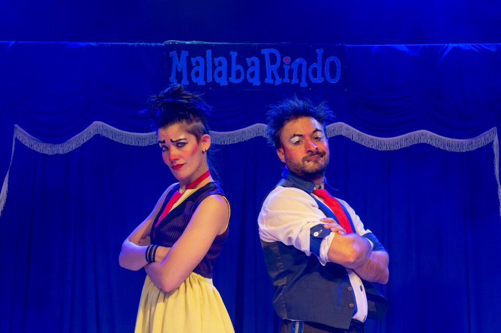 uma mulher ao lado de um homem com figurinos de palhaços