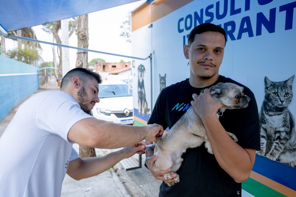 Rapaz de camiseta escura seguro o seu cãozinho para ser vacinado