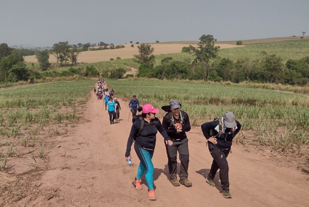 pessoas caminhando em estrada de terra, com mochilas nas costas e roupas de trekking