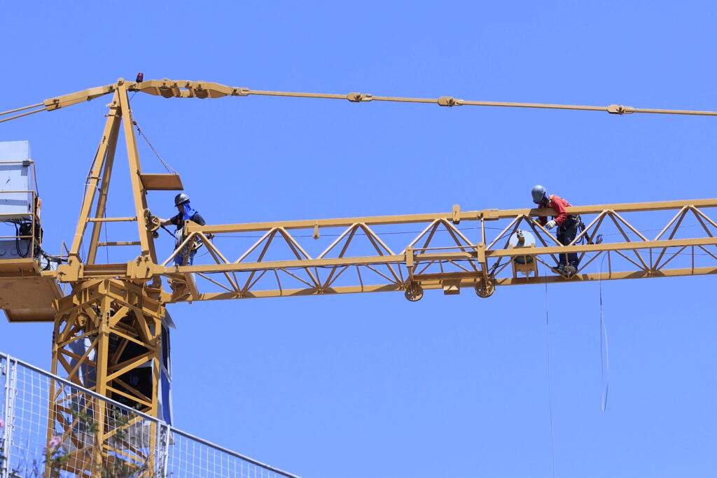 Em um guindaste, trabalhadores da construção civil fazer obras em um prédio
