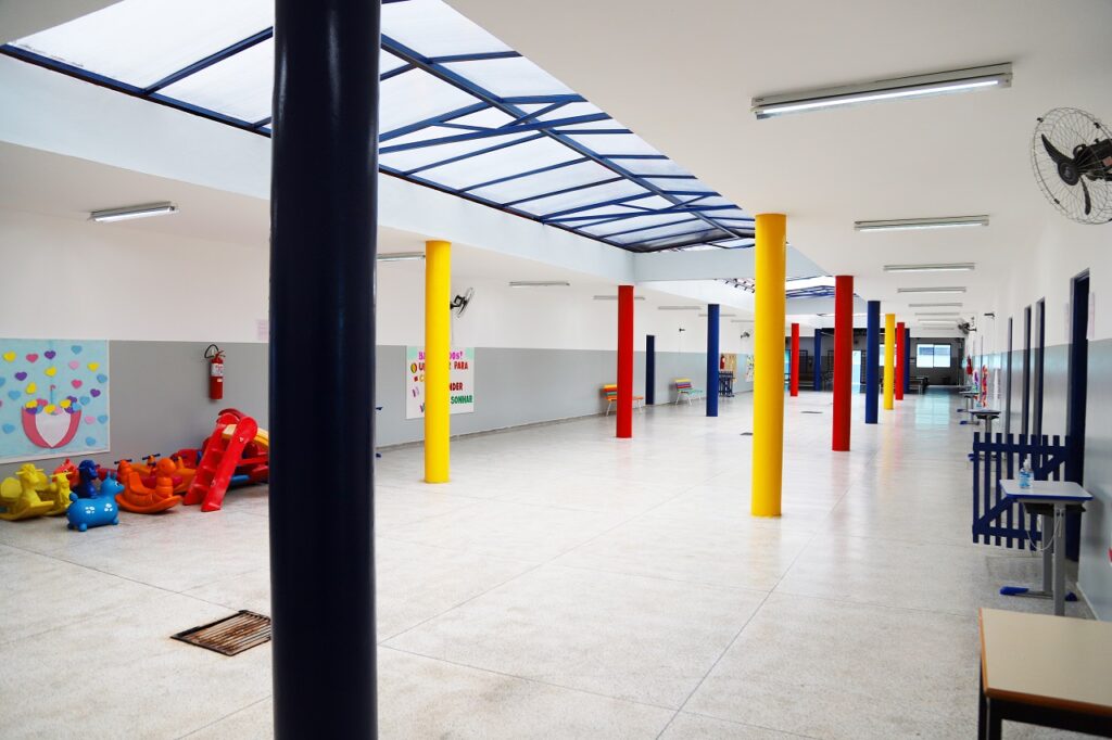 Imagem do pátio interno da escola, mostrando como ficou após a reforma com as paredes pintadas e as pilastras coloridas