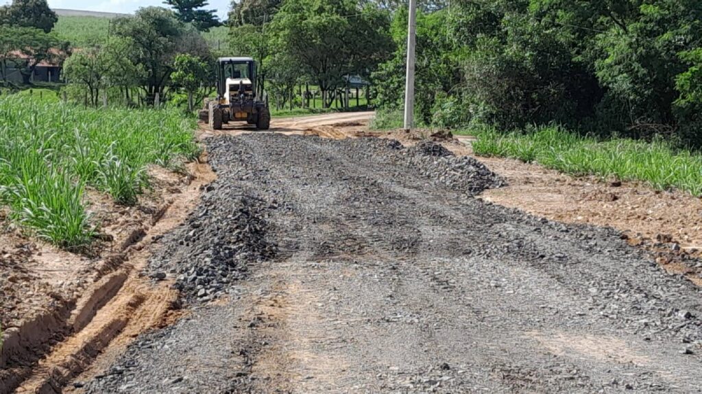 Trator trabalhando em estrada aplicando lajão britado em estrada de terra