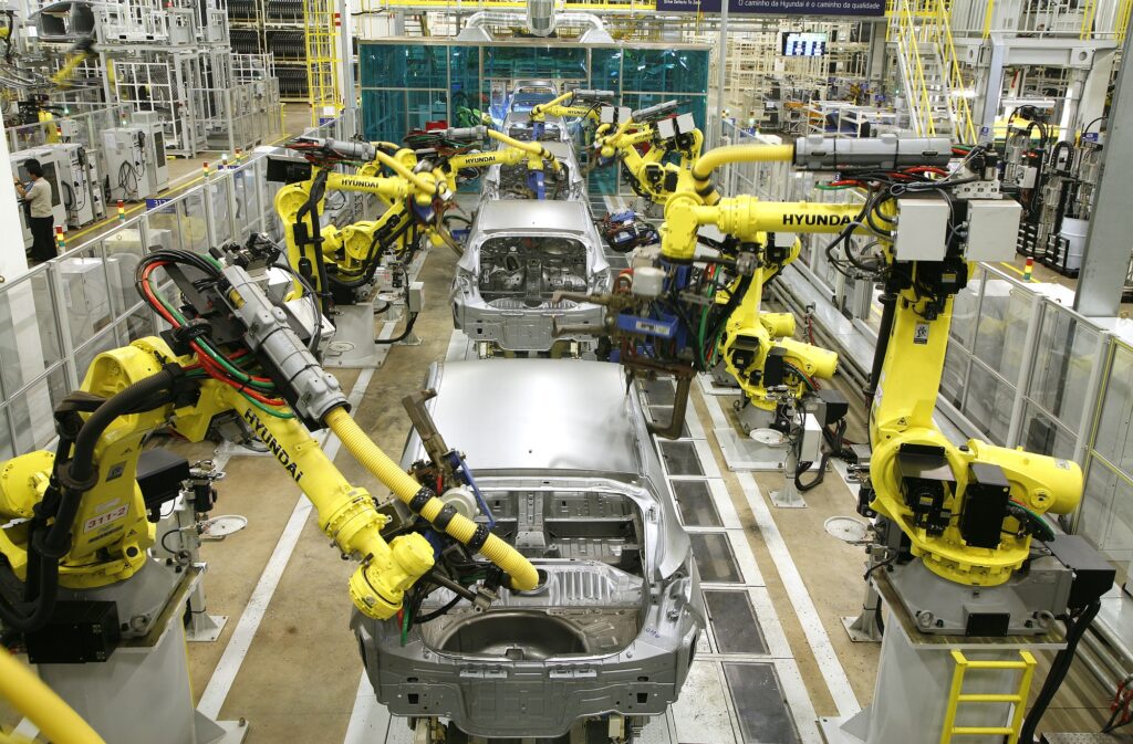 foto mostra o interior de uma fábrica onde são montados carros