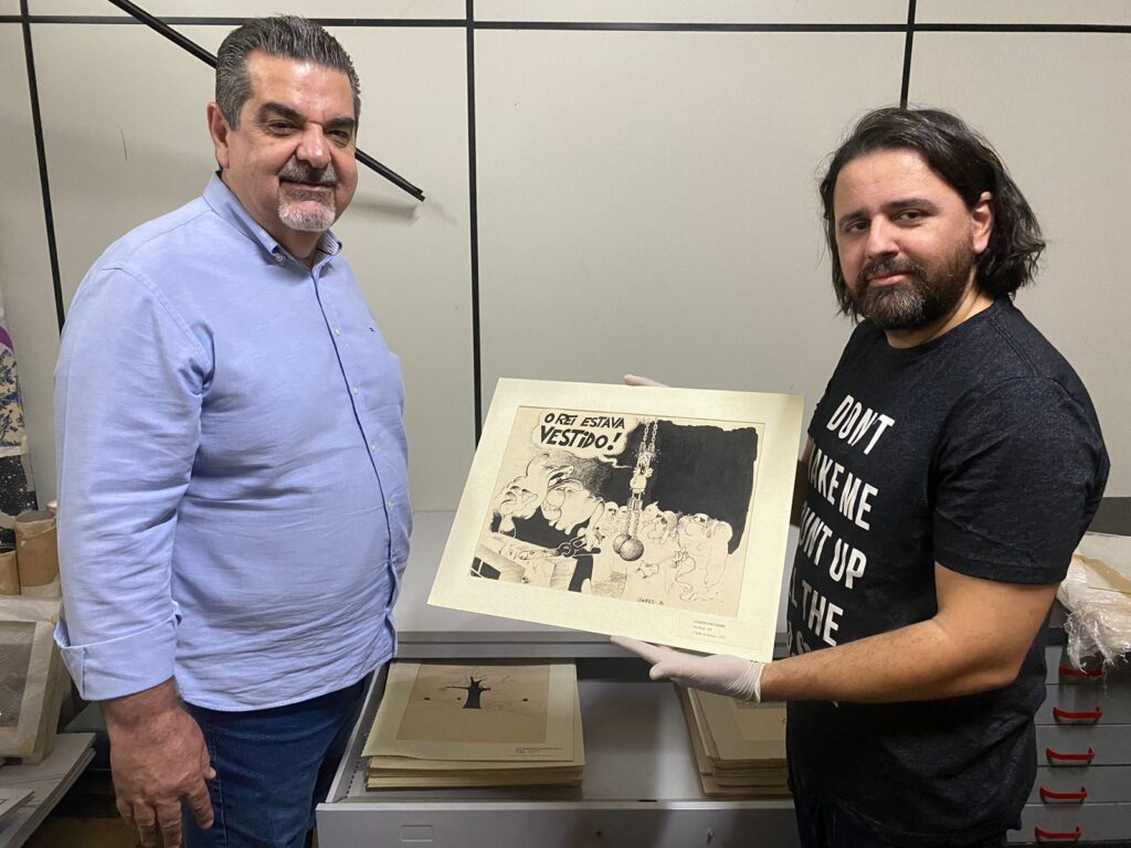 Kadeshi mostra obra recebida para o primeiro Salão de Humor, em 1974, junto ao secretário Carlos Beltrame