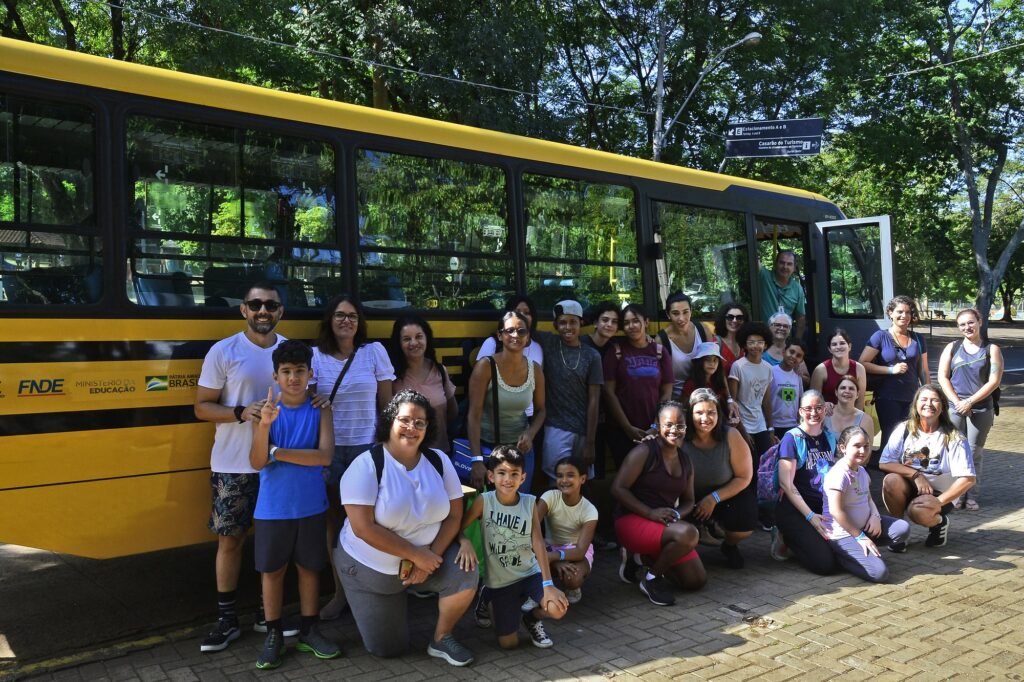 pessoas em pé e agachadas em frente à ônibus