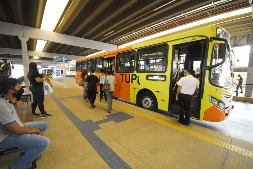 Ônibus com detalhes em amarelo e laranja, estacionado no Terminal de Ônibus.