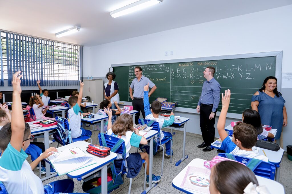 dois homens em pé em sala de aula com diversos alunos