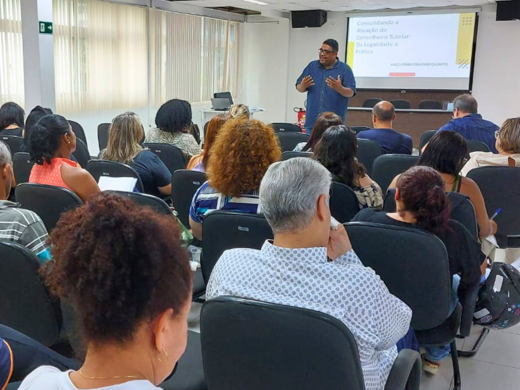 Na imagem, ao fundo, Marcelo Nascimento fala aos participantes de palestra no Guarujá