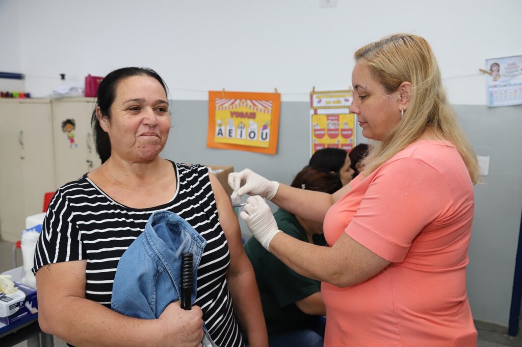 Mulher com camiseta listradas toma vacina.