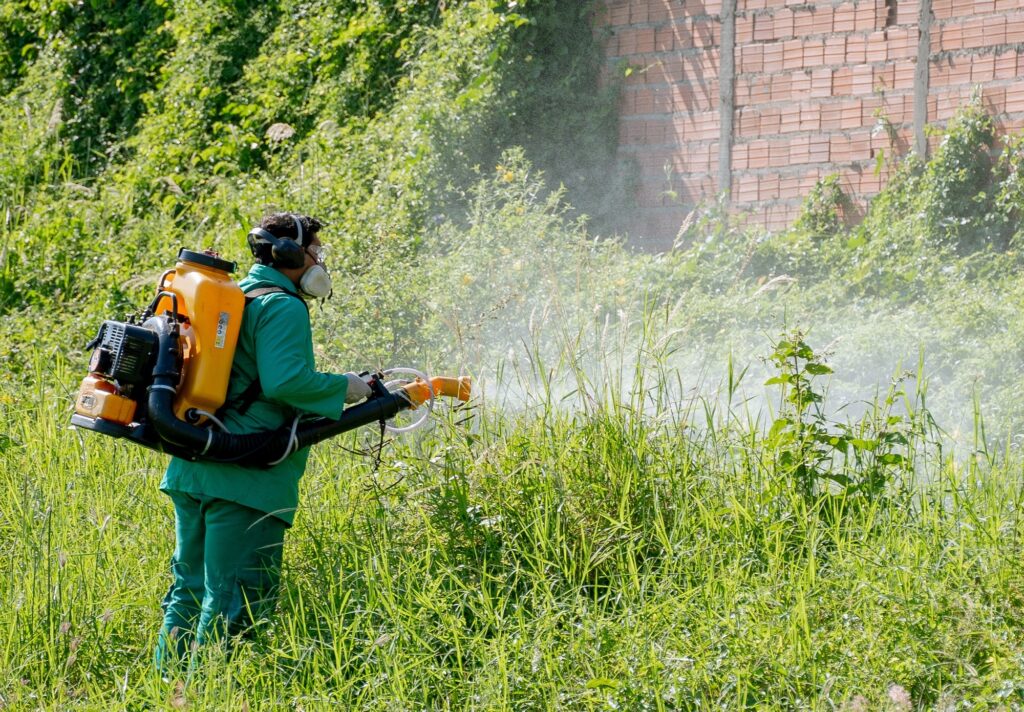Homem pulveriza matagal para combater o mosquito da dengue