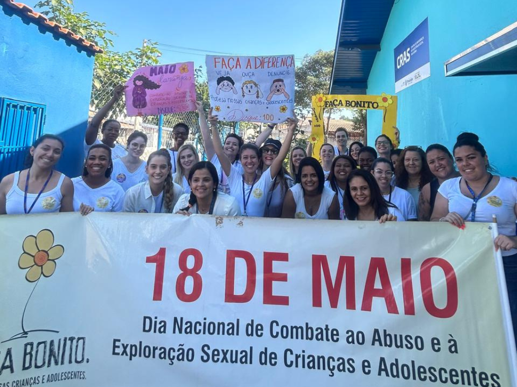 Na imagem pessoas seguram a faixa 18 de maio - Dia Nacional de Combate ao Abuso e exploração sexual de crianças e adolescentes