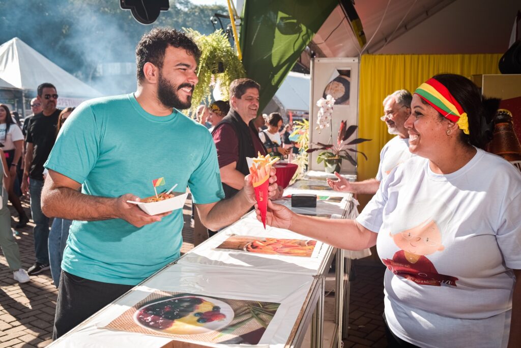 Rapaz pegando alimento na Festa das Nações.