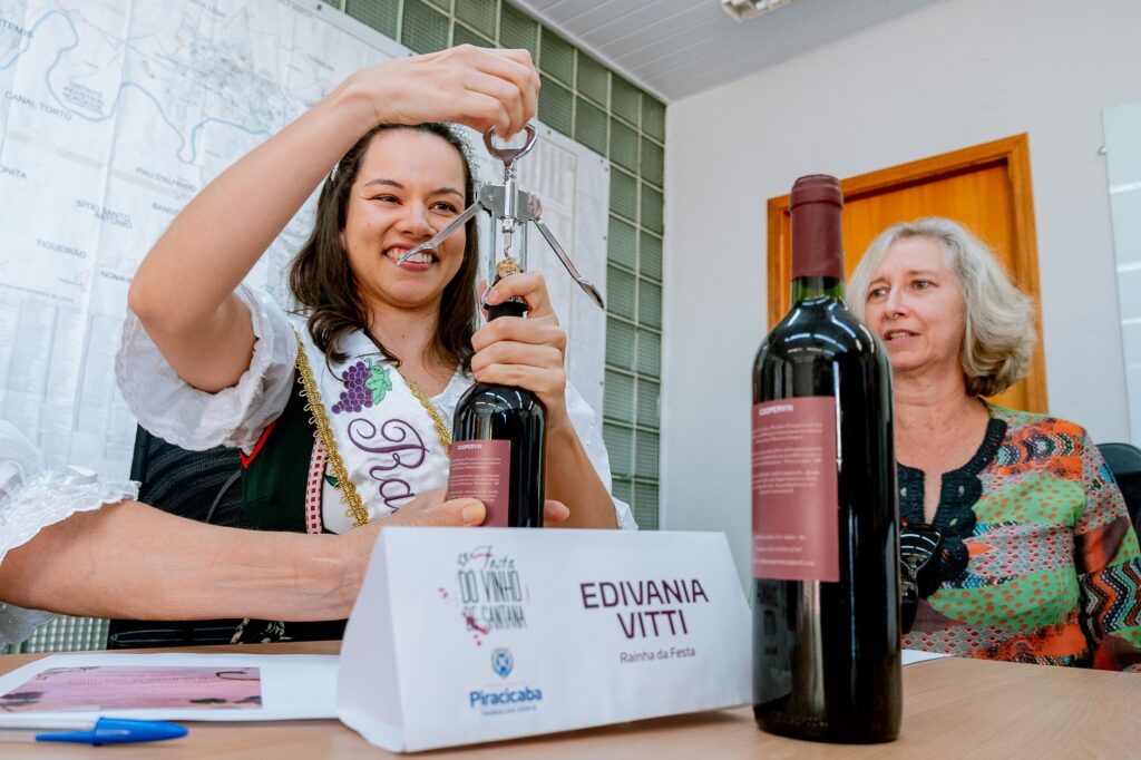 Edivinia Vitti abre um vinho ao lado de Vera Negri