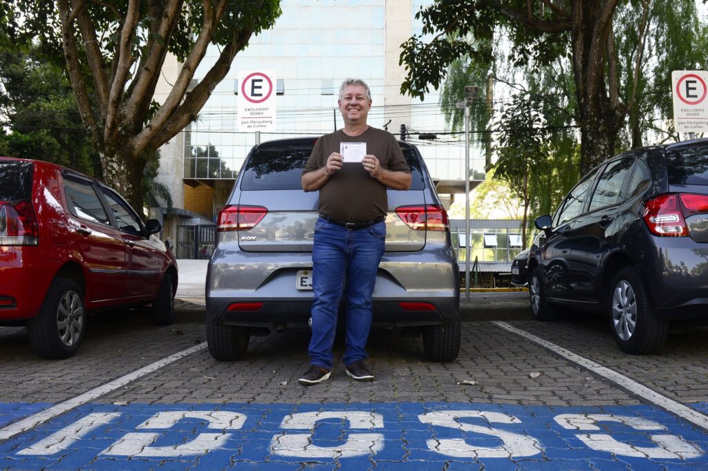 Homem segura a credencial para estacionamento de idoso.