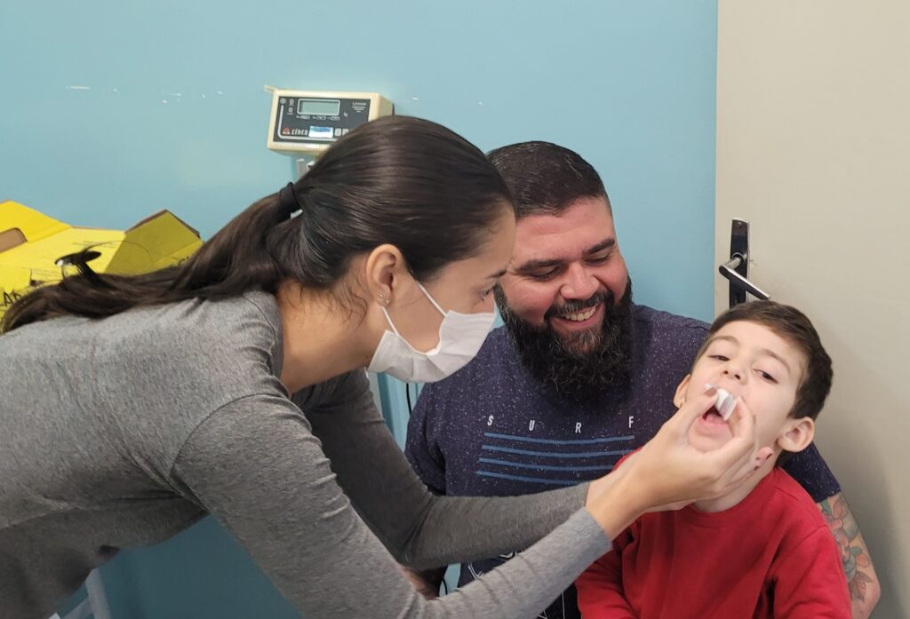 Criança recebe gotinha da vacina na boca.
