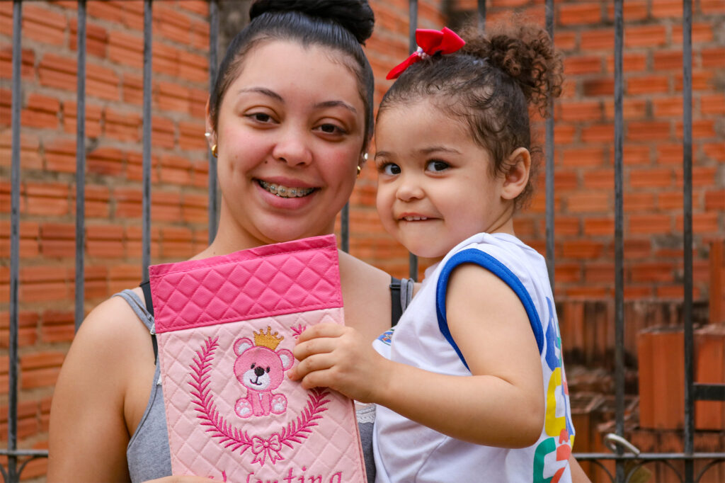 Ao lado da mãe, Flávia, a pequena Valentina de 3 anos mostra com orgulho sua carteira de vacinação