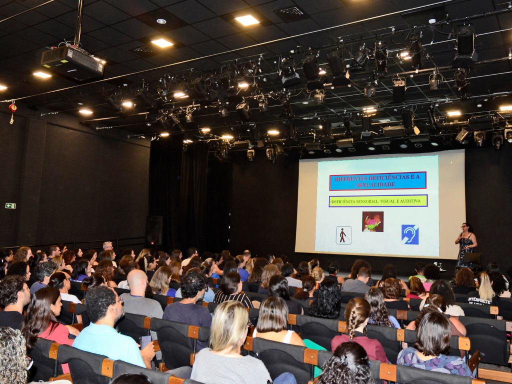 Na imagem, a palestrante Ana Cláudia fala ao público, com recursos audiovisuais, no teatro do Sesc Piracicaba