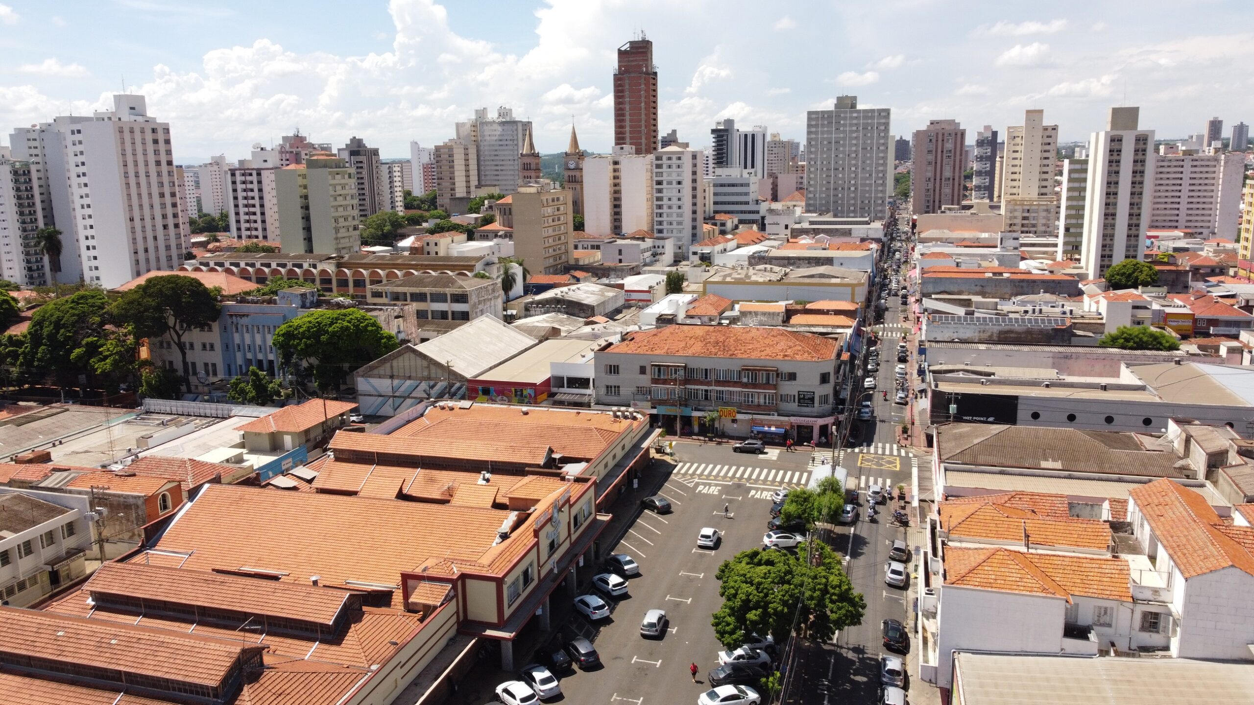 imagem mostra uma visão aérea da cidade, na região central, mostrando o Mercado Municipal e ruas movimentadas do comércio