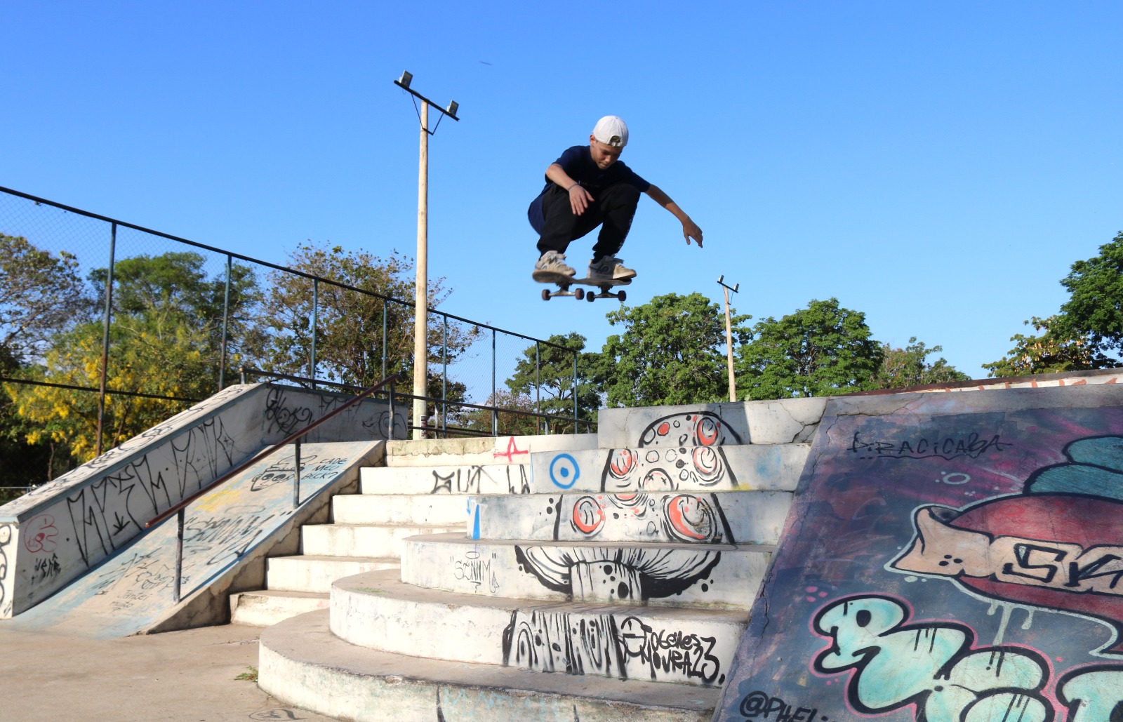 Garoto com roupa escura azul, faz manobra de skate, no Parque da Rua do Porto. O nome dele é Igor e pratica a modalidade há vários anos.
