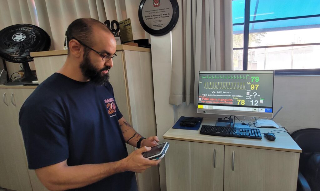 Rafael, médico do Samu, mostra como controlar as emoções do manequim simulador com tablet na mão e condições de saúde simuladas em tela de computador