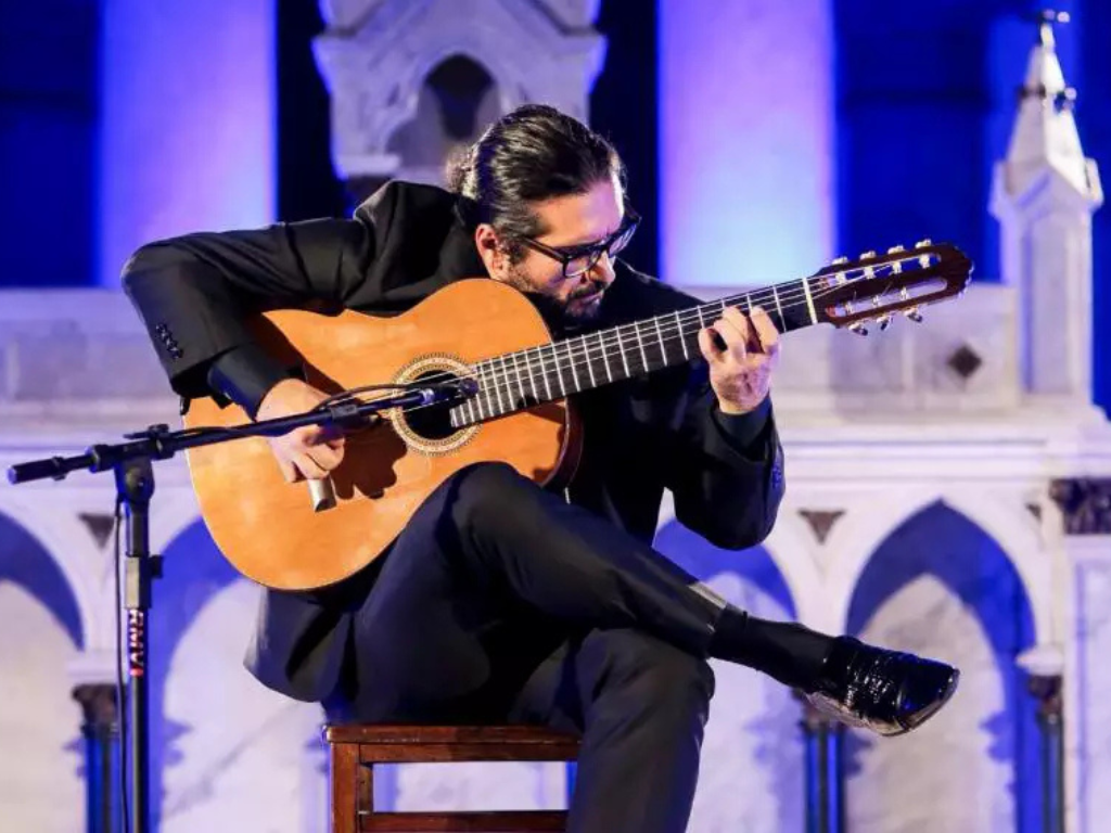 Imagem do músico Alessandro Penezzi, tocando violão