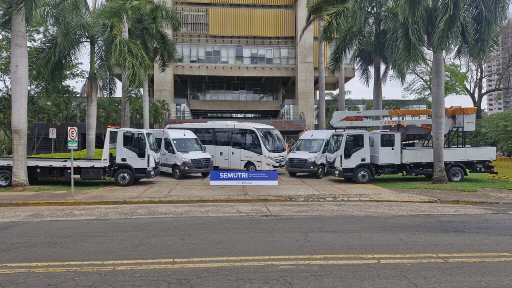 Van e caminhões da cor clara, estacionados na rampa do Centro Cívico da Prefeitura.