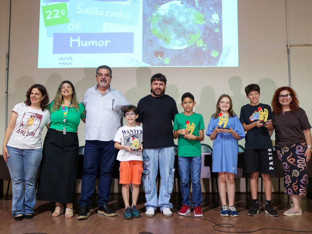 Na imagem, crianças e adolescentes premiados, junto à equipe do Salãozinho, posam para foto em cima do palco onde ocorreram as premiações